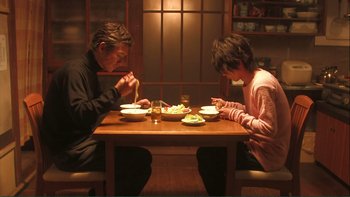 Movie still from “Love Exposure” (2008), directed by Sion Sono – A man and a woman sitting at a dinner table; Medium shot, Low angle