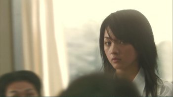 Movie still from “Love Exposure” (2008), directed by Sion Sono – A young asian woman with long black hair looking at the camera; Close Up shot, Over the shoulder angle