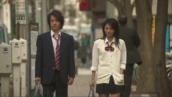 Movie still from “Love Exposure” (2008), directed by Sion Sono – A man and a woman walking down a street; Medium shot, Low angle
