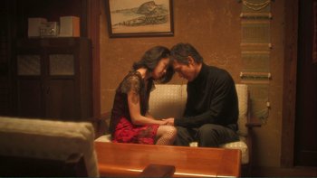 Movie still from “Love Exposure” (2008), directed by Sion Sono – A man and a woman sitting on top of a white couch; Medium shot, High angle