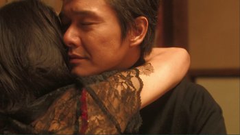 Movie still from “Love Exposure” (2008), directed by Sion Sono – A man is hugging a woman in a black dress; Close Up shot, Over the shoulder angle