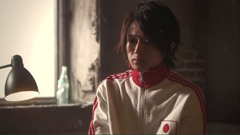 Movie still from “Love Exposure” (2008), directed by Sion Sono – A person wearing a white and red jacket; Close Up shot, Low angle