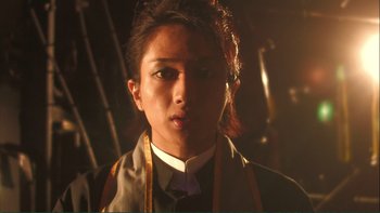Movie still from “Love Exposure” (2008), directed by Sion Sono – A person with long brown hair wearing a tie; Close Up shot, Low angle