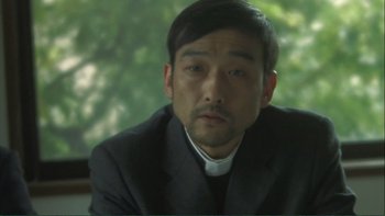 Movie still from “Love Exposure” (2008), directed by Sion Sono – A person wearing a suit and tie; Close Up shot, Low angle
