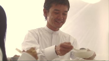 Movie still from “Love Exposure” (2008), directed by Sion Sono – A man sitting at a table with a bowl of food in front of him; Close Up shot, Low angle