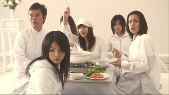 Movie still from “Love Exposure” (2008), directed by Sion Sono – A group of people sitting at a table with food on it; Medium shot, Low angle