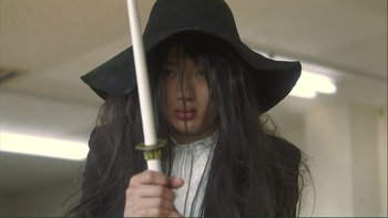Movie still from “Love Exposure” (2008), directed by Sion Sono – A woman with long black hair holding a sword in her hand; Close Up shot, Low angle