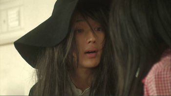 Movie still from “Love Exposure” (2008), directed by Sion Sono – A woman with long black hair wearing a black hat; Close Up shot, Over the shoulder angle