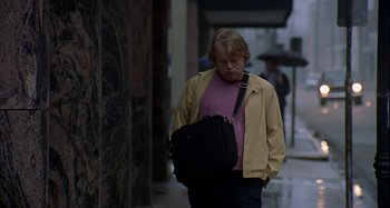 Movie still from “Love Liza” (2002), directed by Todd Louiso – A man walking down a street holding a black bag; Medium shot, Over the shoulder angle