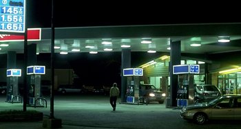 Movie still from “Love Liza” (2002), directed by Todd Louiso – A man walking down the street at a gas station at night; Wide shot, Over the shoulder angle