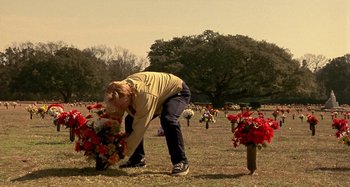 Movie still from “Love Liza” (2002), directed by Todd Louiso – A woman bending over to pick up flowers from a grave; Wide shot, Over the shoulder angle