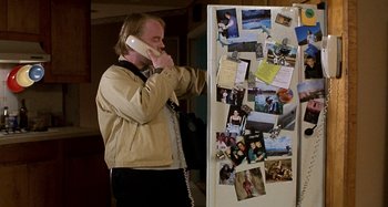 Movie still from “Love Liza” (2002), directed by Todd Louiso – A man standing next to a refrigerator talking on the phone; Medium shot, High angle