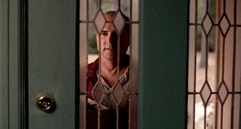 Movie still from “Love Liza” (2002), directed by Todd Louiso – A man standing in front of an open door; Medium shot, Low angle