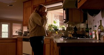 Movie still from “Love Liza” (2002), directed by Todd Louiso – A person standing in a kitchen next to a counter; Medium shot, Low angle