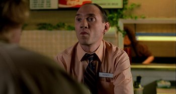 Movie still from “Love Liza” (2002), directed by Todd Louiso – A man in a shirt and tie is sitting at a table in a restaurant; Close Up shot, Low angle