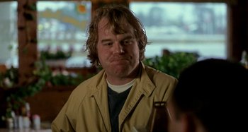 Movie still from “Love Liza” (2002), directed by Todd Louiso – A person sitting at a table with a guitar; Close Up shot, Over the shoulder angle