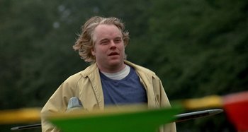 Movie still from “Love Liza” (2002), directed by Todd Louiso – A man with blonde hair is standing outside; Close Up shot, Over the shoulder angle