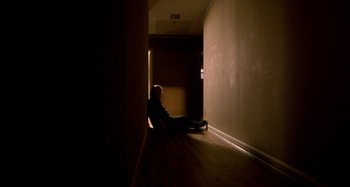 Movie still from “Love Liza” (2002), directed by Todd Louiso – A man sitting on the ground in a dark room; Wide shot, High angle