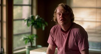 Movie still from “Love Liza” (2002), directed by Todd Louiso – A man with blonde hair sitting in front of a window; Close Up shot, Over the shoulder angle