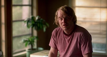 Movie still from “Love Liza” (2002), directed by Todd Louiso – A man with blonde hair wearing a pink shirt; Close Up shot, Over the shoulder angle