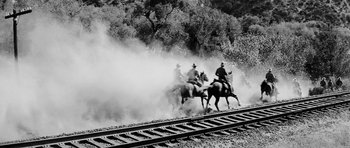 Movie still from “Love Me Tender” (1956), directed by Robert D. Webb – A group of men riding horses down a train track; Wide shot, Low angle