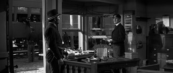 Movie still from “Love Me Tender” (1956), directed by Robert D. Webb – Two men standing in front of a table; Medium shot, Over the shoulder angle
