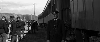 Movie still from “Love Me Tender” (1956), directed by Robert D. Webb – A man in a uniform standing in front of a train; Wide shot, Low angle