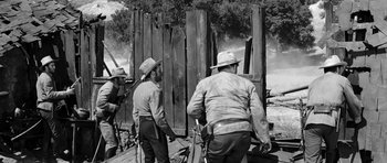 Movie still from “Love Me Tender” (1956), directed by Robert D. Webb – A black and white photo of a group of men standing next to each other; Wide shot, Over the shoulder angle