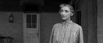Movie still from “Love Me Tender” (1956), directed by Robert D. Webb – An older woman standing in front of a brick building; Close Up shot, Over the shoulder angle