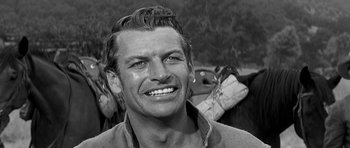 Movie still from “Love Me Tender” (1956), directed by Robert D. Webb – Black and white photograph of a man smiling for the camera; Close Up shot, Low angle