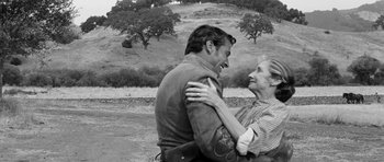 Movie still from “Love Me Tender” (1956), directed by Robert D. Webb – A man and a woman hugging in a field; Medium shot, Over the shoulder angle