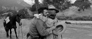 Movie still from “Love Me Tender” (1956), directed by Robert D. Webb – A man and a woman hug in a field; Medium shot, Over the shoulder angle