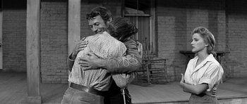 Movie still from “Love Me Tender” (1956), directed by Robert D. Webb – A man and a woman hugging on a porch; Medium shot, Over the shoulder angle