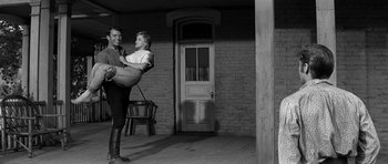 Movie still from “Love Me Tender” (1956), directed by Robert D. Webb – A man and a woman standing in front of a brick building; Wide shot, Low angle