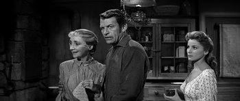 Movie still from “Love Me Tender” (1956), directed by Robert D. Webb – An older man and woman standing next to each other in a kitchen; Medium shot, Over the shoulder angle
