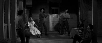 Movie still from “Love Me Tender” (1956), directed by Robert D. Webb – A man and a woman are playing a guitar while another man and woman watch; Wide shot, Over the shoulder angle