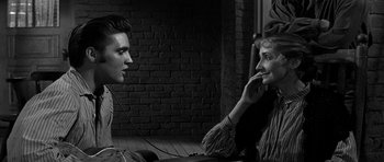 Movie still from “Love Me Tender” (1956), directed by Robert D. Webb – A man and a woman sitting next to each other on the ground; Close Up shot, Over the shoulder angle
