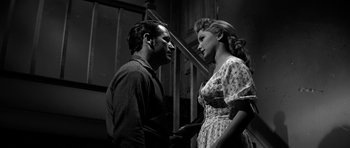 Movie still from “Love Me Tender” (1956), directed by Robert D. Webb – A man and a woman standing next to each other in front of a staircase; Medium shot, Low angle
