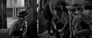Movie still from “Love Me Tender” (1956), directed by Robert D. Webb – A black and white photo of a man milking a horse; Medium shot, Low angle