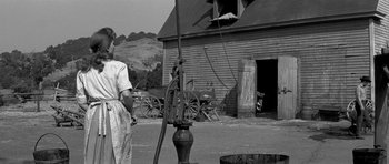 Movie still from “Love Me Tender” (1956), directed by Robert D. Webb – An old photo of a man pumping water out of a well; Wide shot, Low angle