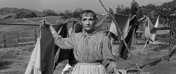 Movie still from “Love Me Tender” (1956), directed by Robert D. Webb – An old photo of a woman hanging clothes on a clothesline; Medium shot, Low angle
