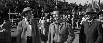 Movie still from “Love Me Tender” (1956), directed by Robert D. Webb – A black and white photo of a man in a crowd; Medium shot, Over the shoulder angle