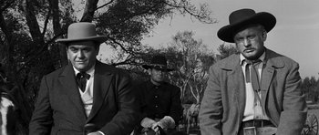 Movie still from “Love Me Tender” (1956), directed by Robert D. Webb – A group of men sitting next to each other on a field; Medium shot, Low angle