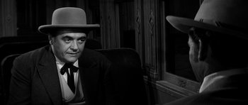 Movie still from “Love Me Tender” (1956), directed by Robert D. Webb – A black and white photo of a man wearing a hat; Close Up shot, Over the shoulder angle