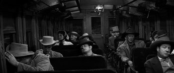 Movie still from “Love Me Tender” (1956), directed by Robert D. Webb – A black and white photo of people sitting on a train; Medium shot, High angle