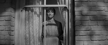 Movie still from “Love Me Tender” (1956), directed by Robert D. Webb – A woman standing in front of a window; Medium shot, Low angle