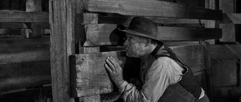 Movie still from “Love Me Tender” (1956), directed by Robert D. Webb – An old man smoking a cigarette next to a wooden wall; Medium shot, Over the shoulder angle