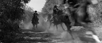 Movie still from “Love Me Tender” (1956), directed by Robert D. Webb – A black and white photo of a group of people riding horses; Wide shot, Low angle