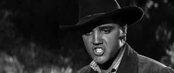 Movie still from “Love Me Tender” (1956), directed by Robert D. Webb – A black and white photo of a man in a cowboy hat; Close Up shot, Low angle