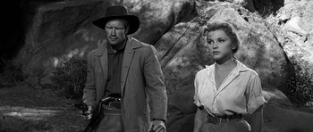 Movie still from “Love Me Tender” (1956), directed by Robert D. Webb – A man and a woman standing next to each other in front of rocks; Medium shot, Low angle